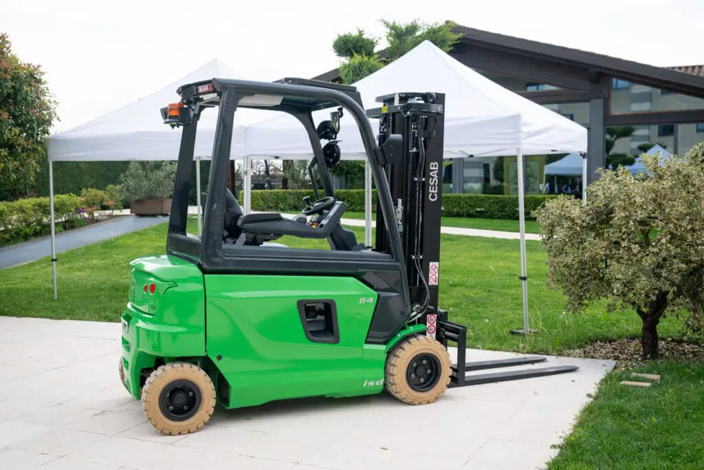 Groene CESAB B420 heftruck in gebruik in een magazijn vol gestapeld karton, gezien vanuit achteraanzicht. — Prins Maasdijk