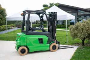 Groene CESAB B420 heftruck in gebruik in een magazijn vol gestapeld karton, gezien vanuit achteraanzicht. — Prins Maasdijk