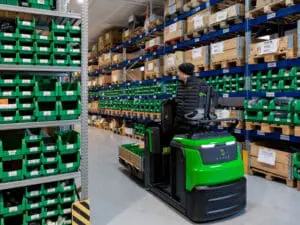 Magazijnmedewerker transporteert pallet met CESAB O1 elektrische palletwagen in smal gangpad van onderdelen magazijn | Prins Maasdijk