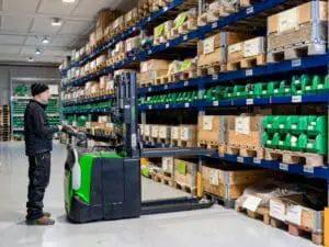 Magazijnmedewerker bedient CESAB S320DN elektrische stapelaar bij stellingen in onderdelen magazijn | Prins Maasdijk
