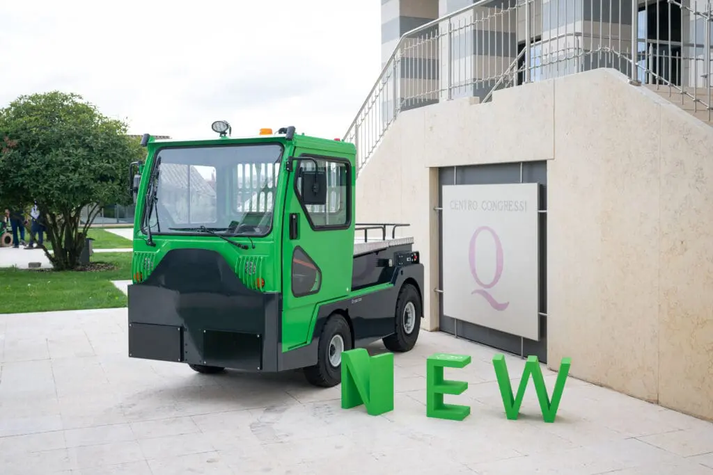 Groene elektrische trekker (Tracto TE252) voor een congrescentrum met grote groene "NEW"-letters op de voorgrond. — Prins Maasdijk