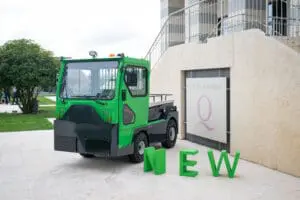 Groene elektrische trekker (Tracto TE252) voor een congrescentrum met grote groene "NEW"-letters op de voorgrond. — Prins Maasdijk