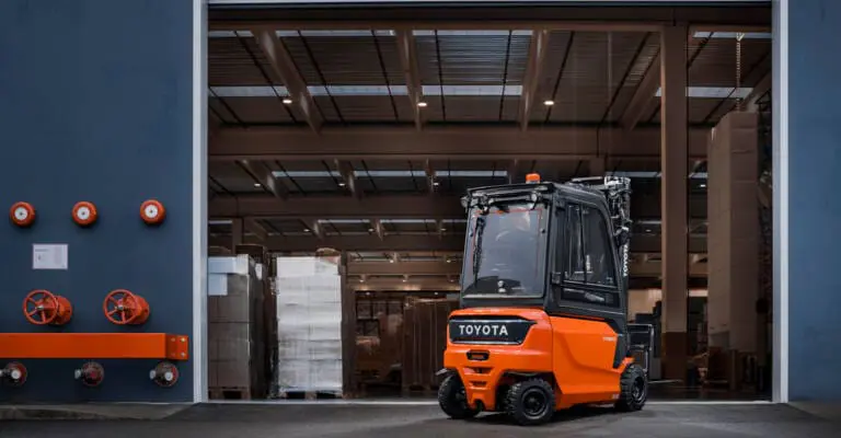 Toyota Traigo 48V 4-wiel elektrische heftruck rijdend bij laaddock van industrieel magazijn | Prins Maasdijk