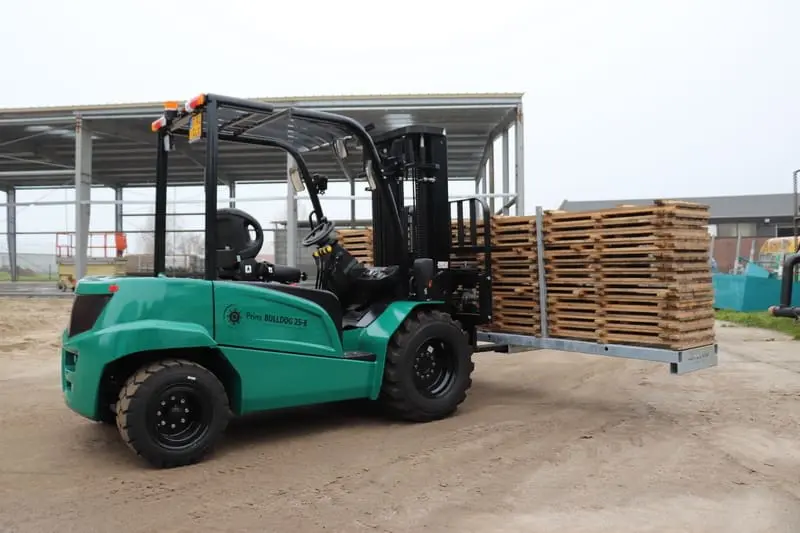 Groene Prins Bulldog 25-E elektrische heftruck met een stapel houten pallets op een buitenterrein, linker zijaanzicht. — Prins Maasdijk