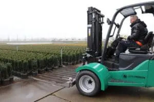 Bestuurder op een groene Prins Tiger XXL-E Zero Emission heftruck die planten oppikt op een buitenterrein. — Prins Maasdijk