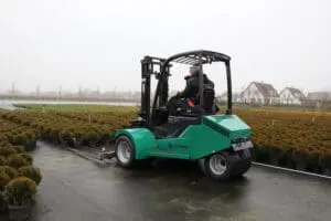 Bestuurder op een groene Prins Tiger XXL-E Zero Emission heftruck in gebruik op een buitenkwekerij met potplanten. — Prins Maasdijk