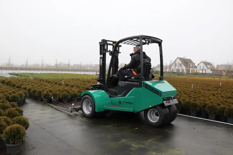 Bestuurder op een groene Prins Tiger XXL-E Zero Emission heftruck in gebruik op een buitenkwekerij met potplanten. — Prins Maasdijk