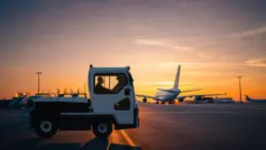 Toyota Tracto TE501 elektrisch transportvoertuig op luchthavenplatform bij zonsondergang met vliegtuig op de achtergrond | Prins Maasdijk