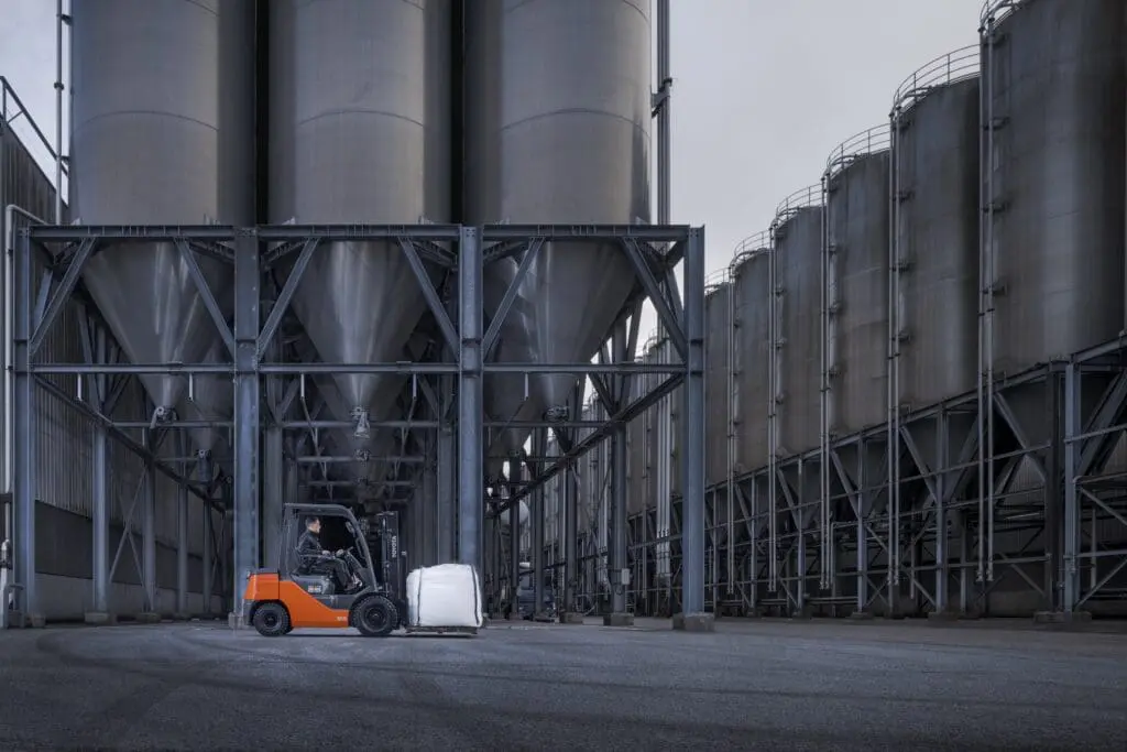 Magazijnmedewerker transporteert bigbag met Toyota Tonero LPG heftruck bij industriële silo's buitenomgeving | Prins Maasdijk