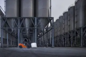 Magazijnmedewerker transporteert bigbag met Toyota Tonero LPG heftruck bij industriële silo's buitenomgeving | Prins Maasdijk