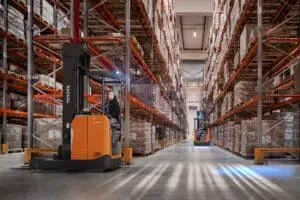 Twee magazijnmedewerkers rijden met Toyota BT Reflex RRE160H reachtrucks in hoog magazijn met palletstellingen | Prins Maasdijk