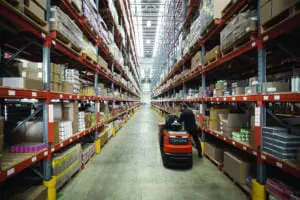 Magazijnmedewerker pickt orders met Toyota BT Optio OSE250 elektrische orderpicker in lang gangpad van groot distributiecentrum | Prins Maasdijk
