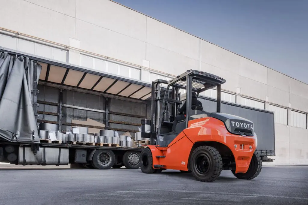 Toyota Traigo 80 elektrische heftruck laadt zware goederen uit vrachtwagen bij laaddok van distributiecentrum | Prins Maasdijk