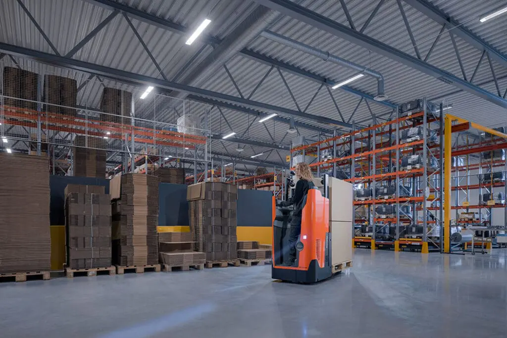 Magazijnmedewerker rijdt met Toyota BT Levio LSI200 elektrische palletwagen in magazijn met hoge stellingen | Prins Maasdijk