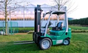 Groene Prins Tiger L heftruck van Prins Maasdijk Vorkheftrucks, vooraanzicht buiten met kassen op de achtergrond. — Prins Maasdijk